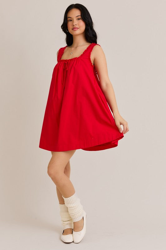 Woman wearing a red dress with white shoes and socks on a plain background