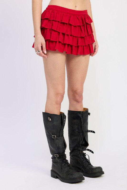 Person wearing a red tiered skirt and black knee-high boots on a white background