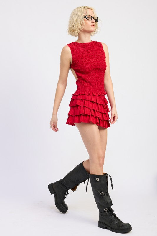 Woman wearing a red dress with ruffles and black boots on a white background