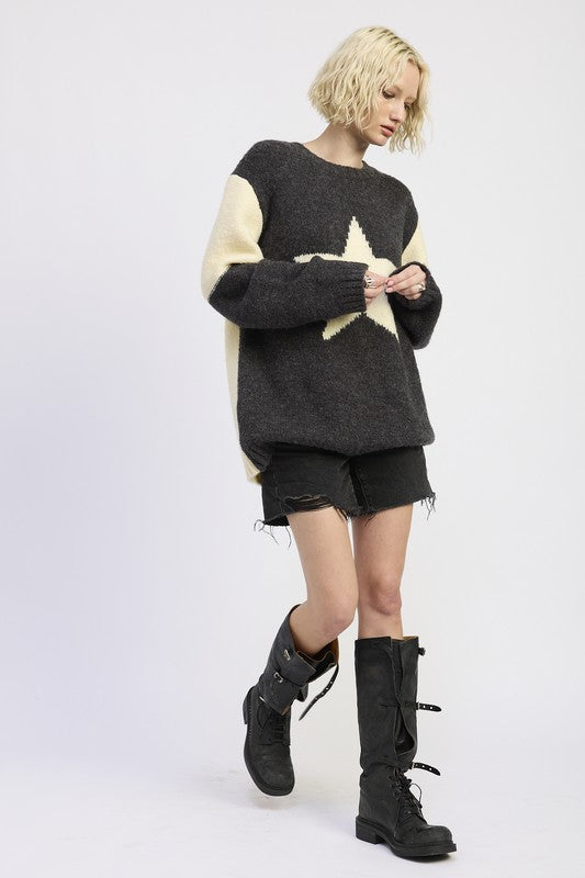 Person wearing a black and beige sweater with shorts and black boots on a white background