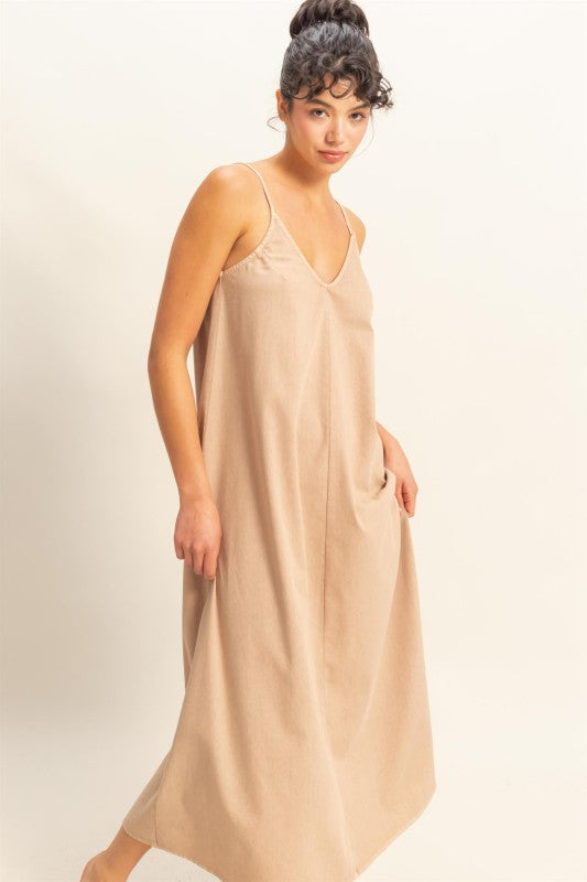 Woman wearing a beige slip dress against a plain background