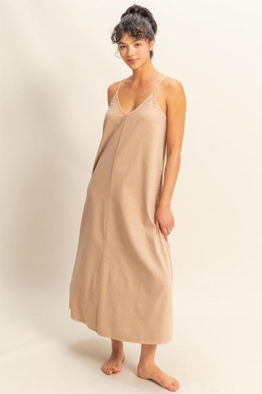 Woman wearing a beige slip dress against a plain background
