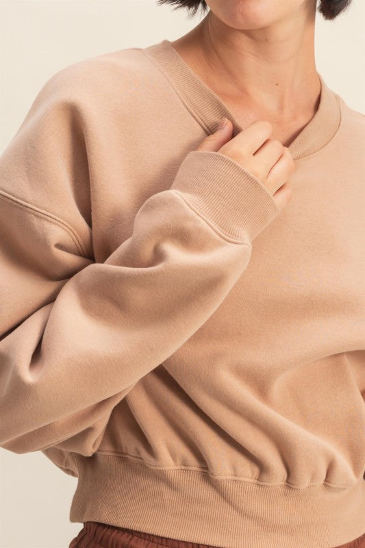 Person wearing a beige sweatshirt against a neutral background
