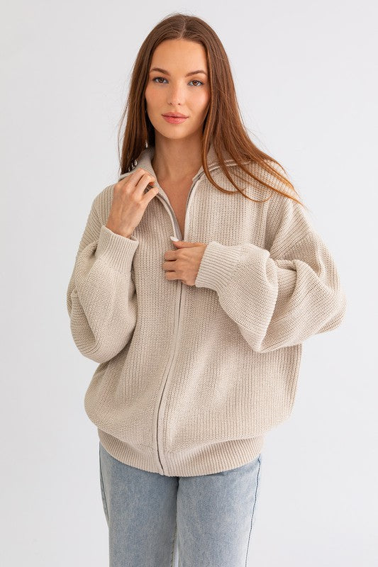 Woman wearing a beige zip-up sweater on a white background