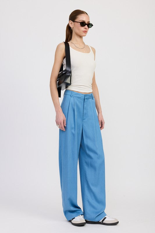 Woman wearing a white top and blue pants with a black bag on a white background