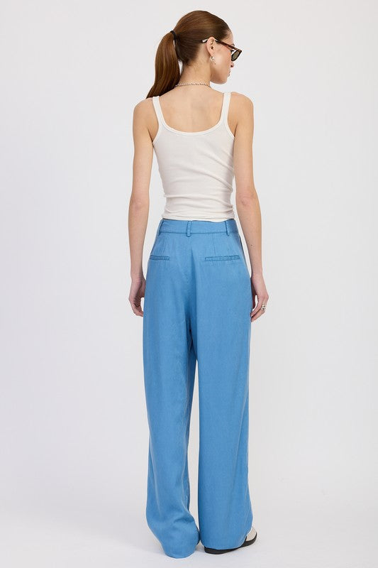Woman wearing a white tank top and blue pants on a white background