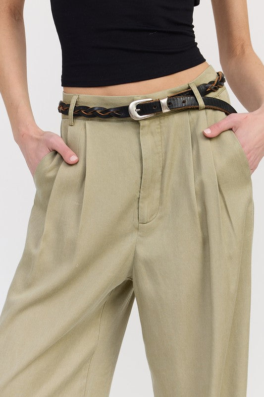 Beige pants with a belt worn by a person on a white background