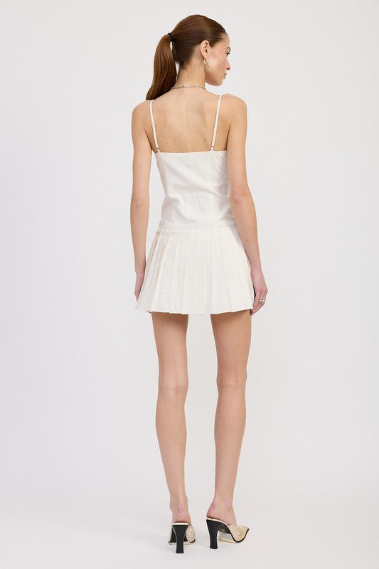 Woman wearing a white dress with thin straps on a plain background