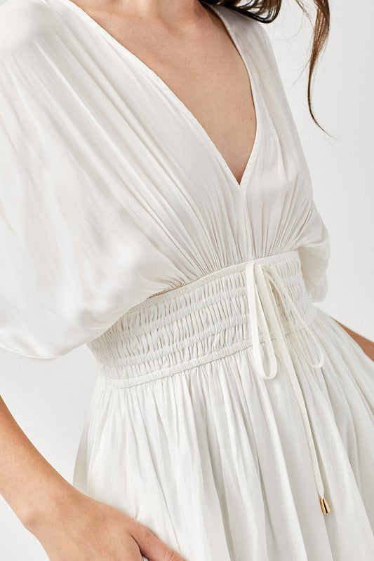 White dress with a deep neckline and smocked waistband on a white background