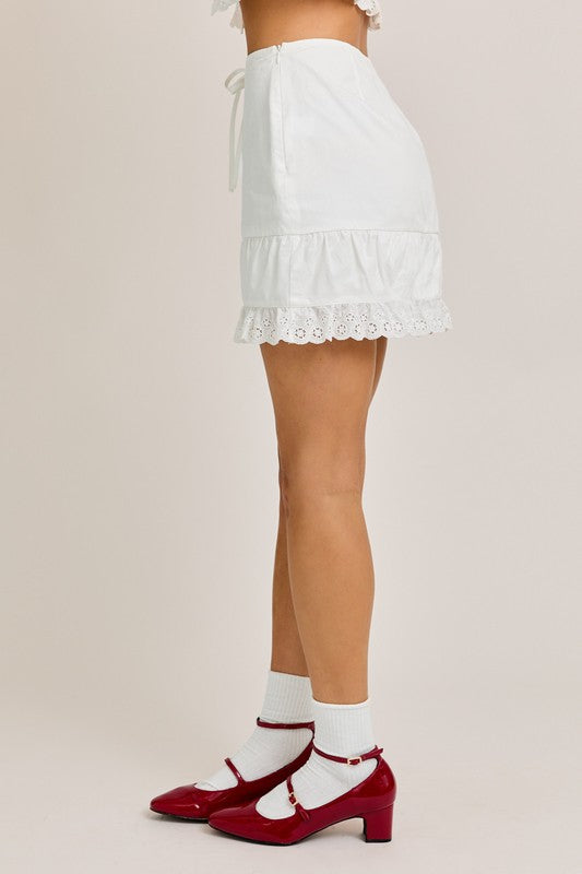 Woman wearing a white skirt and red heels.