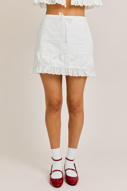 Woman wearing a white skirt and red shoes.