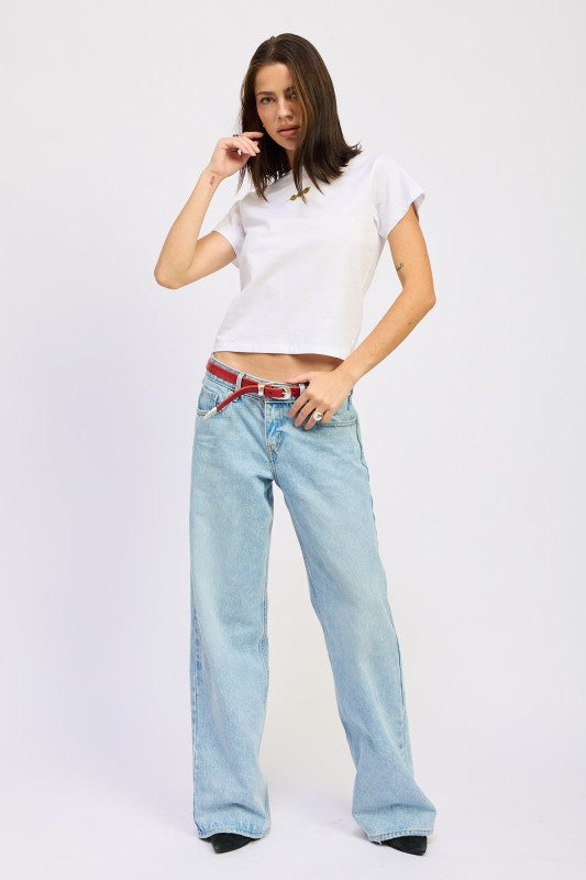 Woman wearing a white t-shirt and light blue jeans on a plain background