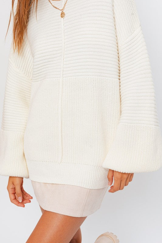 White ribbed sweater worn by a person on a light gray background