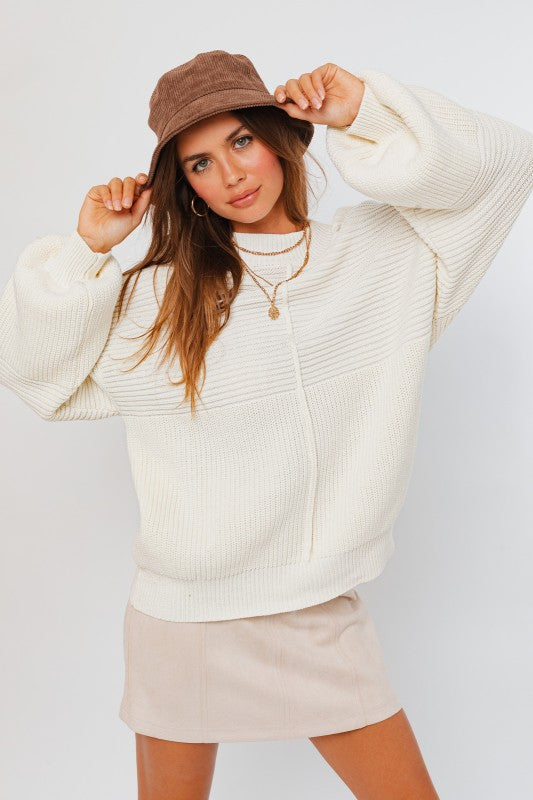 Woman wearing a cream sweater and beige hat against a white background