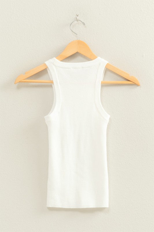 White tank top on a wooden hanger against a beige background