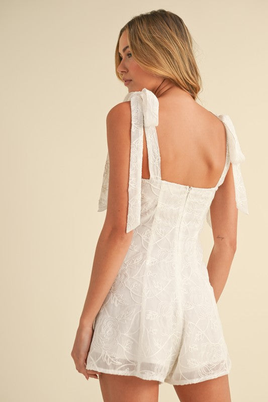 Woman in white lace romper, back view.