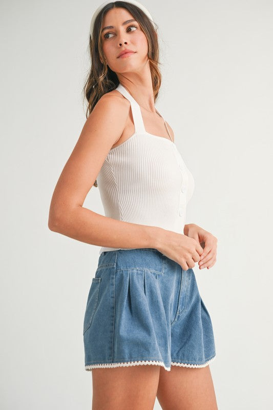 Woman in white top and blue denim shorts.