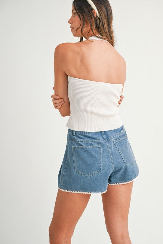 Woman in a white top and denim shorts.
