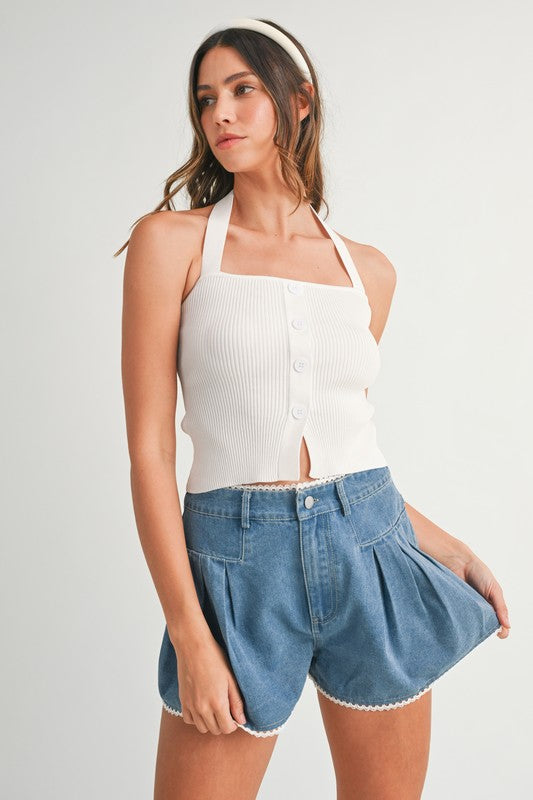 Woman in white halter top and denim shorts.
