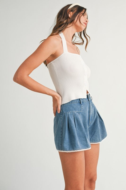 Woman wearing a white halter top and denim shorts.