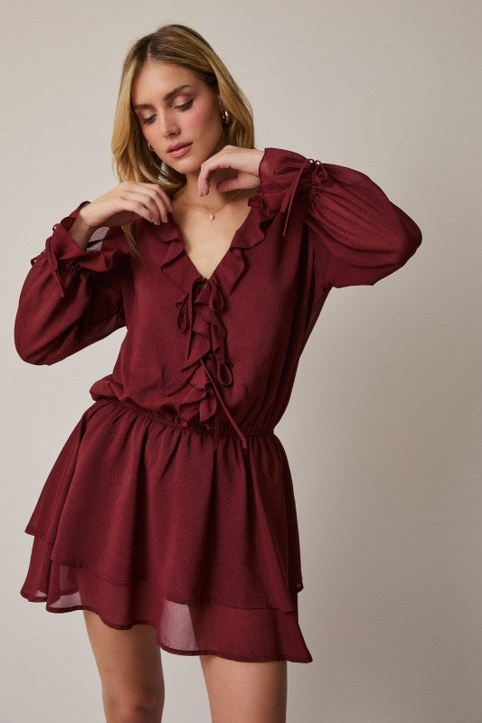 Woman wearing a burgundy dress with long sleeves against a neutral background