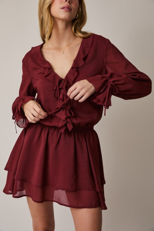 Woman wearing a burgundy dress with long sleeves on a plain background
