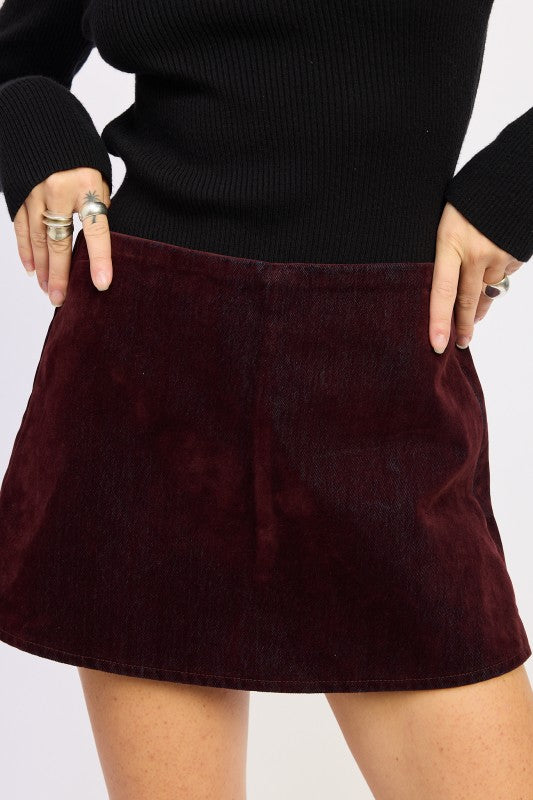 Burgundy skirt worn with a black top on a white background